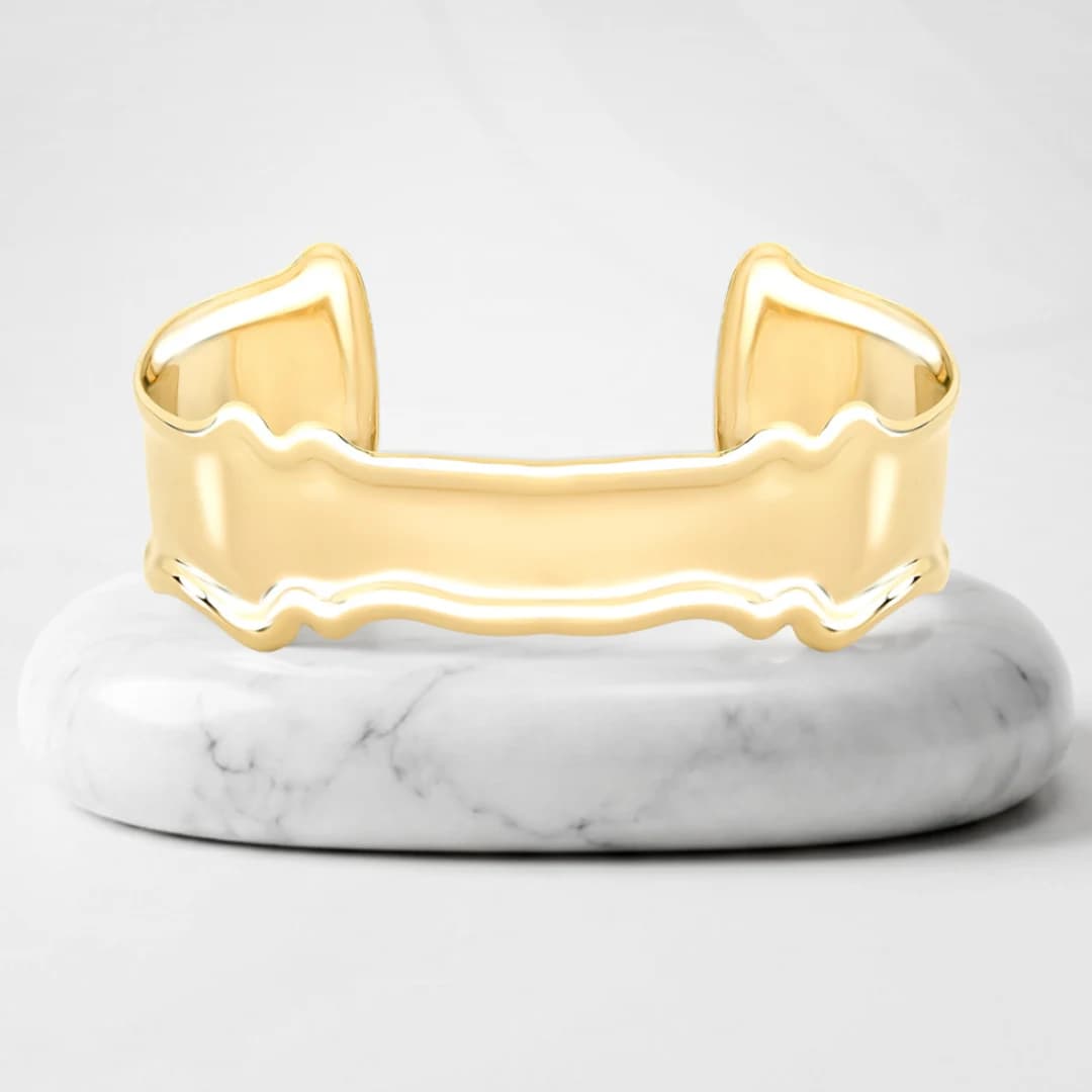 Cuff bracelet with Bari gold plating on a marble pedestal