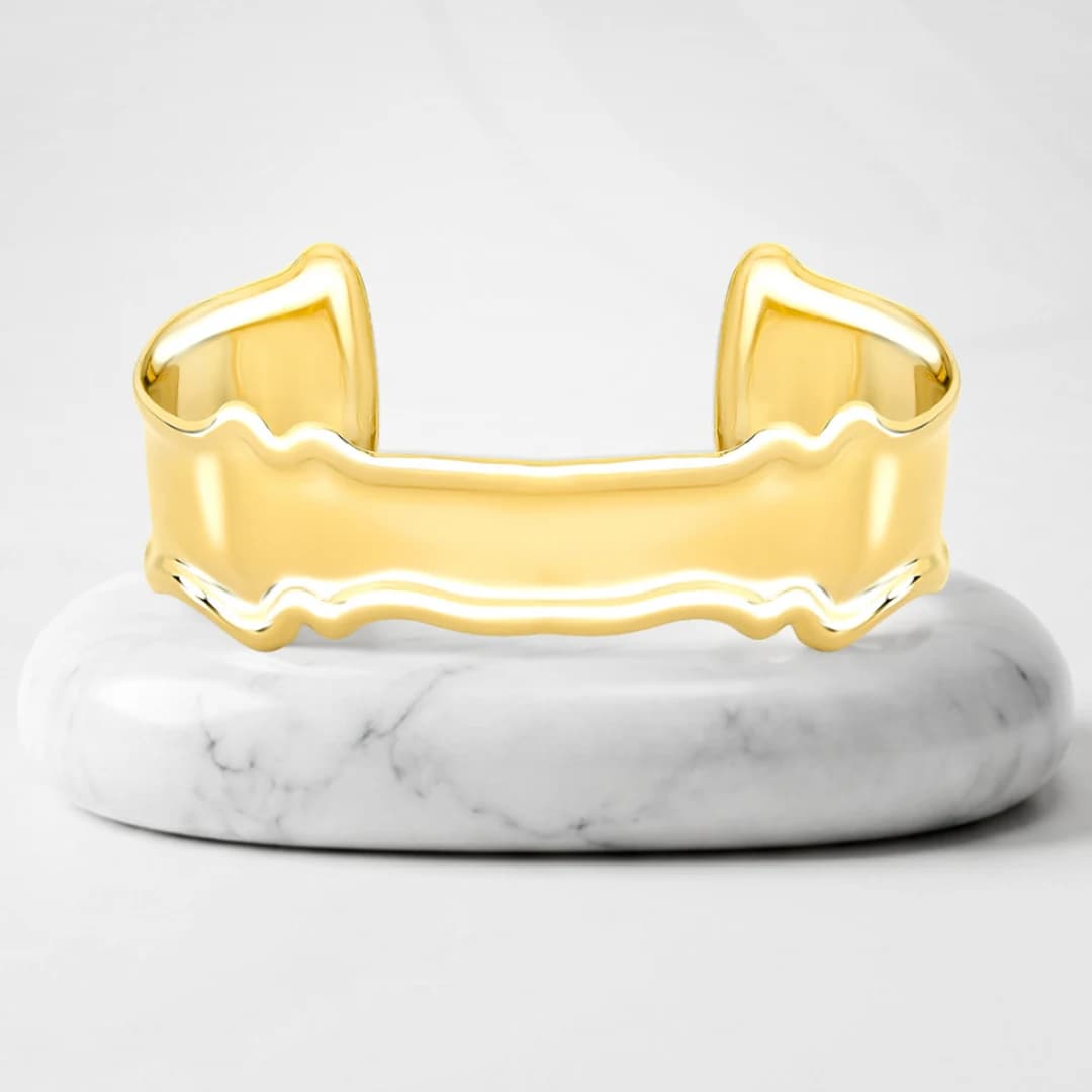 Cuff bracelet with Quebec gold plating on a marble pedestal