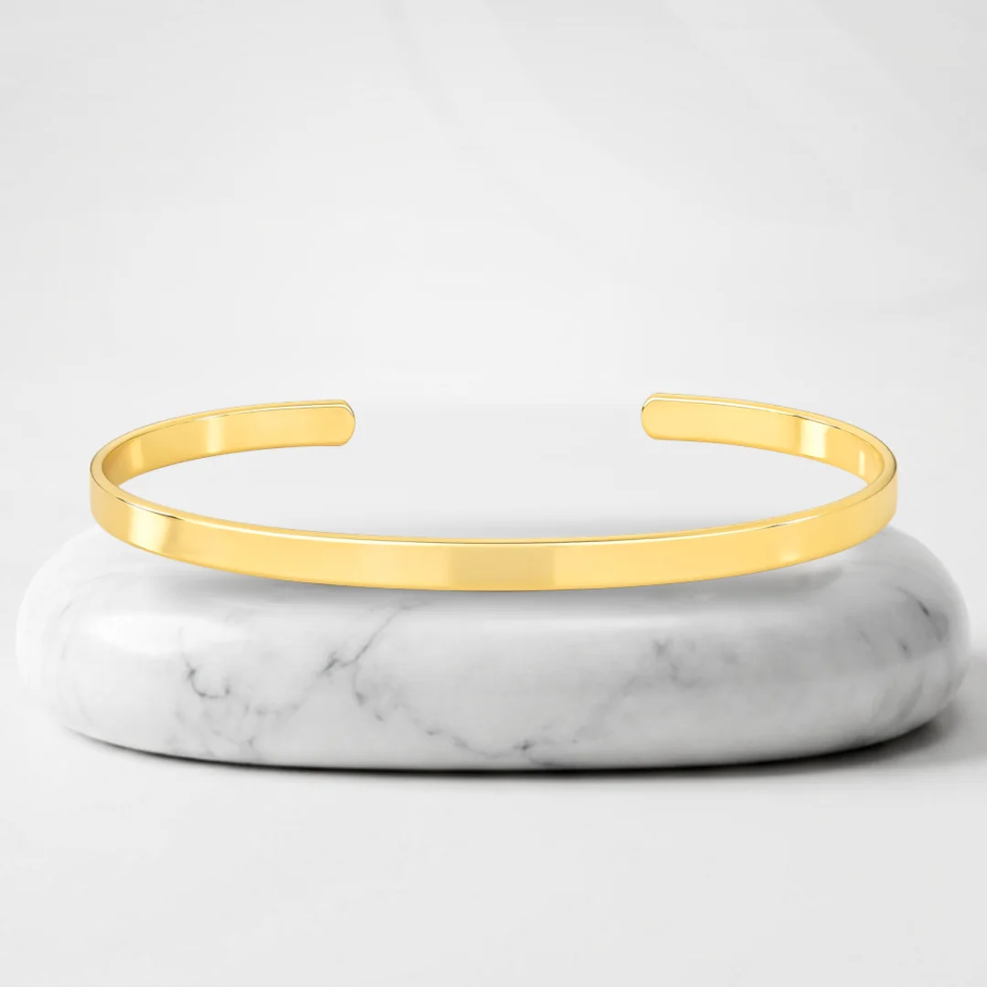 Thin bangle with Quebec gold plating on a marble pedestal
