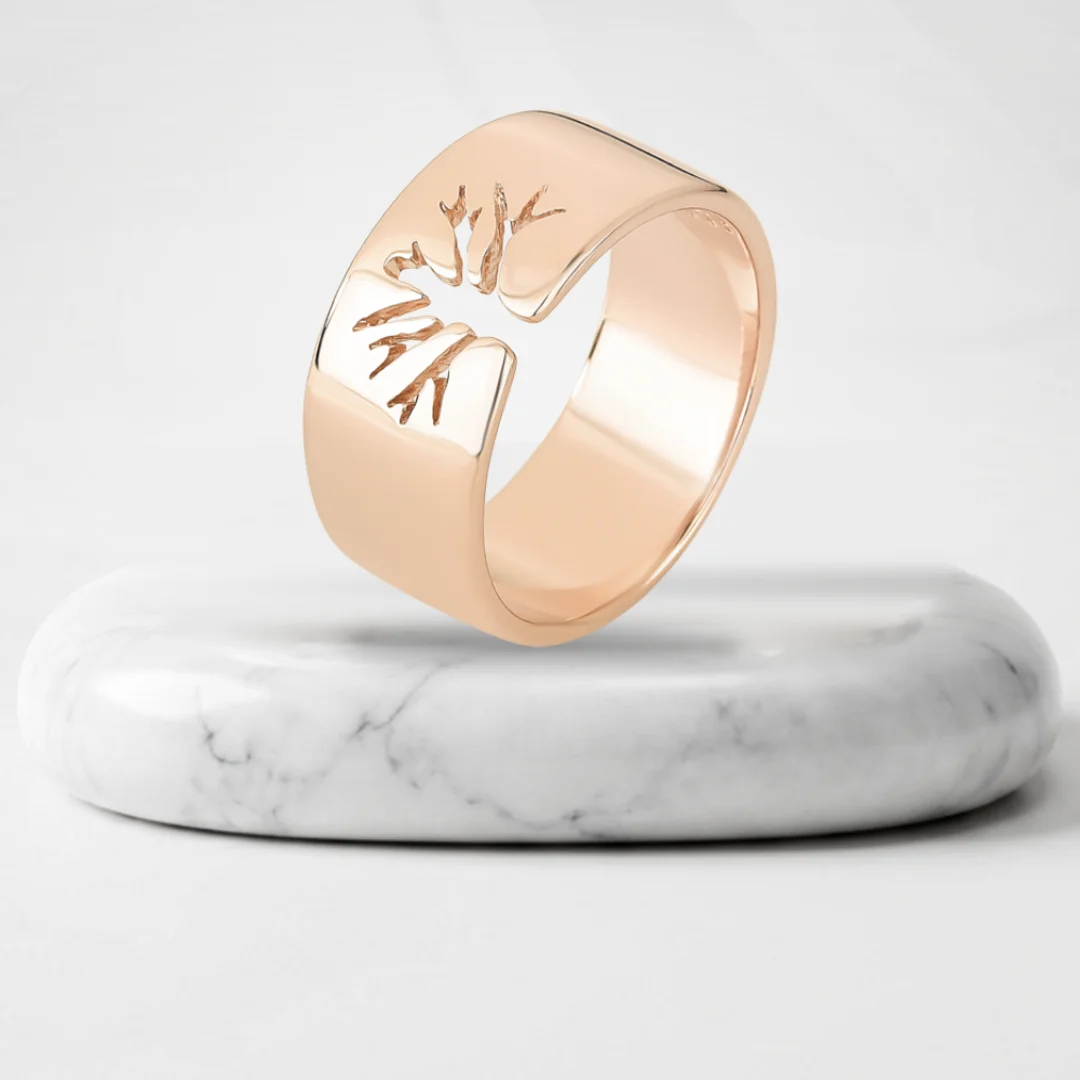 Anillo con árbol calado con baño de oro Riviera sobre un pedestal de mármol