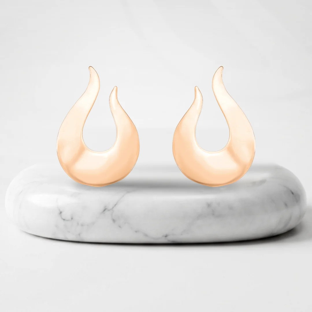 Openwork drop shaped earrings with Vienna gold plating on a marble pedestal